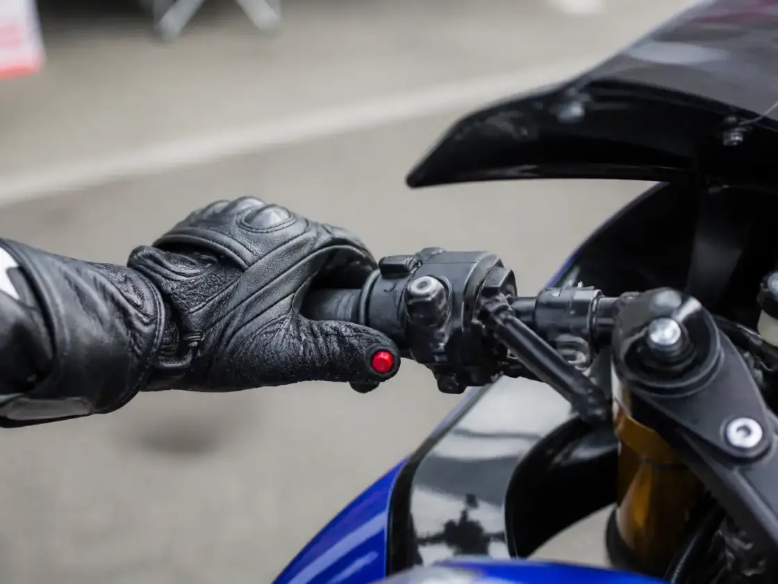 Poignée gauche d’un guidon de moto de circuit, avec un bouton rouge d’arrêt moteur bien visible sous le pouce