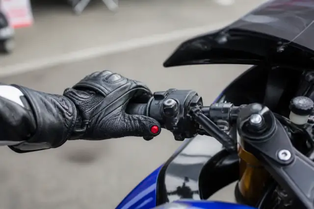 Poignée gauche d’un guidon de moto de circuit, avec un bouton rouge d’arrêt moteur bien visible sous le pouce