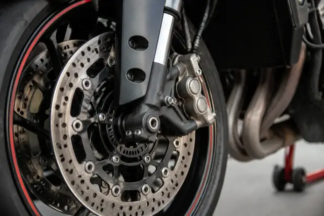Disque de frein avant et étrier d’une moto sportive vus de près, jante sombre, éclairage de studio sobre