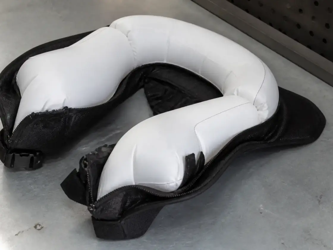 Gilet airbag de moto déployé, posé à plat sur un établi gris, coussin gonflé autour du dos et de la nuque, éclairage neutre