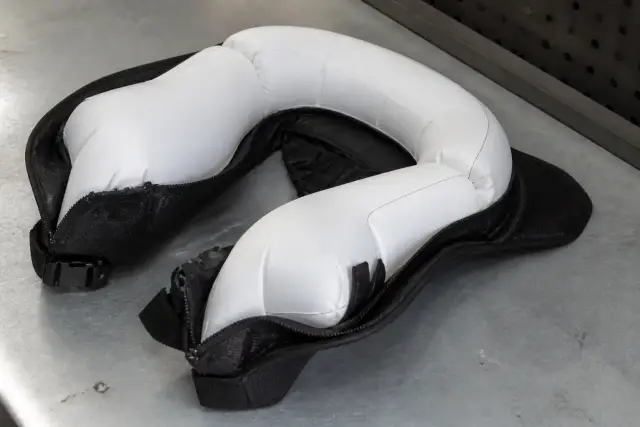 Gilet airbag de moto déployé, posé à plat sur un établi gris, coussin gonflé autour du dos et de la nuque, éclairage neutre