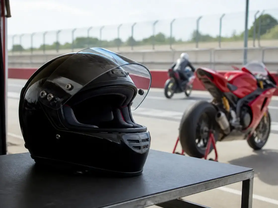 Casque intégral de course posé sur une table de stand, visière relevée, jugulaire apparente, sans marque lisible
